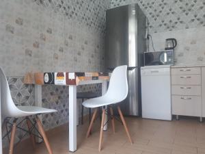 a kitchen with a table with white chairs and a refrigerator at Уютные апартаменты 5 микрорайон in Aktau