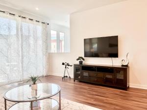 uma sala de estar com uma televisão e uma mesa de vidro em Casa Dolce Vita - A Luxury Modern-Vintage Stay - Get Deals on Monthly - 30-Night Minimum em Irvine