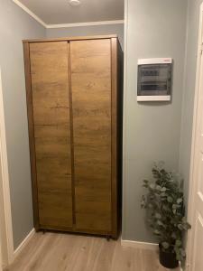 a wooden cabinet in a room with a plant at Strøken liten leilighet i Svolvær. in Svolvær +5 photos