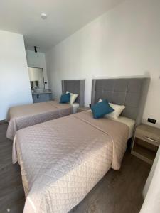 two beds in a hotel room with blue pillows at Riviera Vichayito in Vichayito