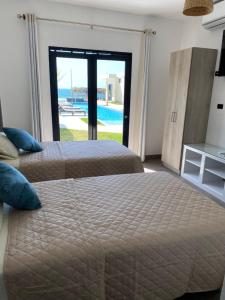 2 Betten in einem Schlafzimmer mit Poolblick in der Unterkunft Riviera Vichayito in Vichayito