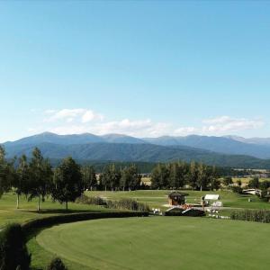 Blick auf einen Golfplatz mit Bergen im Hintergrund in der Unterkunft Allure in Pirin Golf in Raslog