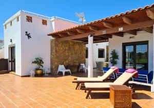 een patio met ligstoelen en stoelen op een huis bij Beautiful Villa Grace, Caleta de Fuste in Caleta De Fuste