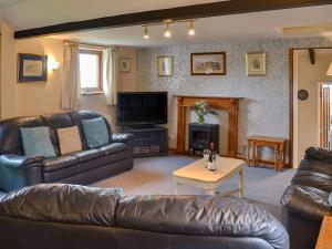 a living room with leather furniture and a tv at Moorview Cottage in Marytavy