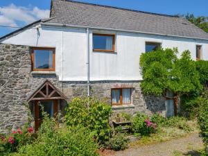 an old stone cottage with windows and flowers in front of it at Moorview Cottage in Marytavy