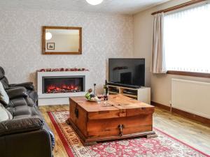 a living room with a coffee table and a fireplace at High Threave Cottage in Kirkcowan