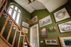 a hallway with green walls and a staircase with framed pictures at Vilegiatura/Florica Socolescu Villa in Sinaia