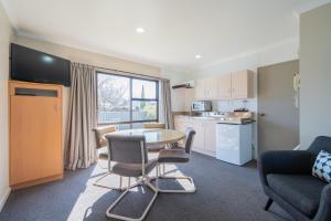a living room with a table and chairs and a kitchen at Te Anau Motel & Apartments in Te Anau