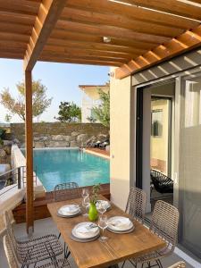 a wooden table and chairs on a patio with a pool at Dimeli - Sea View Villas in Foinikounta in Finikounta