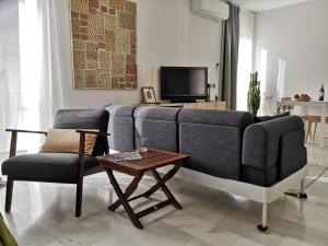 White Loft Alameda في إشبيلية: غرفة معيشة مع أريكة وطاولة وكرسي