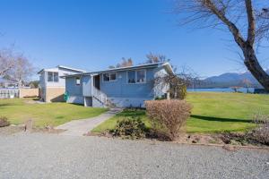 a blue house with a tree and a driveway at Te Anau Motel & Apartments in Te Anau