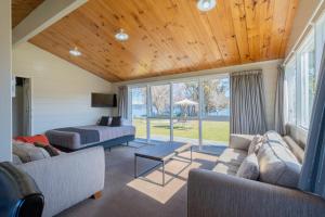 a living room with a couch and a bed and windows at Te Anau Motel & Apartments in Te Anau