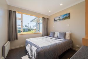 a bedroom with a bed and a large window at Te Anau Motel & Apartments in Te Anau