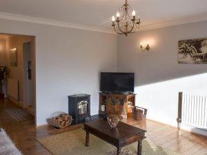 a living room with a fireplace and a tv at Cotswolds Cottage in Hamsterley