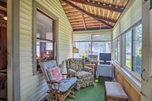 un porche cubierto con 2 sillas y TV en Grandmas Cottage with Sunroom Walk to Beach, en Old Saybrook