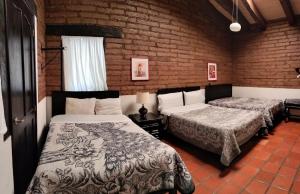 1 dormitorio con 2 camas y pared de ladrillo en Cabañas y habitaciones Los Cedros, en Zacatlán