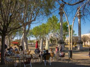 White Loft Alameda في إشبيلية: مجموعة من الناس يجلسون على الطاولات في الحديقة