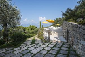 a stone path with a fence and an umbrella at Appartamenti Gianni in Torri del Benaco +27 photos