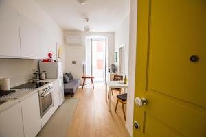 a kitchen with a yellow door and a living room at Casa Imperatrice Sissi in Trieste