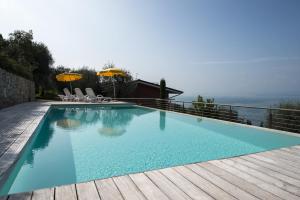 a swimming pool on a deck with chairs and umbrellas at Appartamenti Gianni in Torri del Benaco