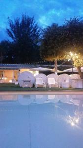 einen Pool mit weißen Liegestühlen neben einem Gebäude in der Unterkunft Parco d'Arte AltArt in Rende