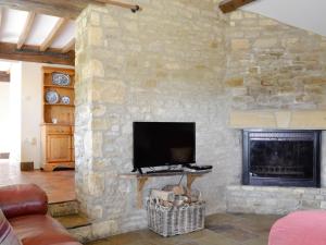 a living room with a stone fireplace and a television at Stable Cottage - Ukc3630 in Adlestrop