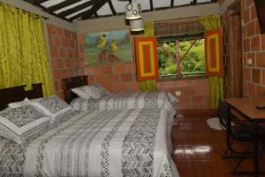 a bedroom with two beds and a table and windows at Finca Hotel Villa Mariana in Montenegro