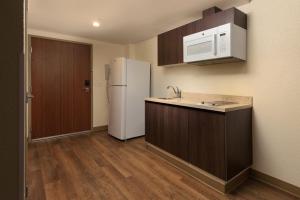 a kitchen with a white refrigerator and wooden cabinets at Extended Suites Merida Siglo XXI in Mérida