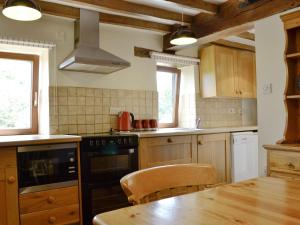 a kitchen with a wooden table and a stove top oven at Stable Cottage - Ukc3630 in Adlestrop