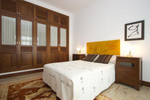 a bedroom with a white bed and wooden cabinets at Villa Remedios in Teguise