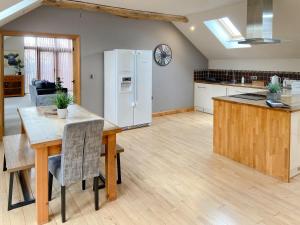 a kitchen and dining room with a table and a refrigerator at Coed Y Nant Barn in Cilybebyll