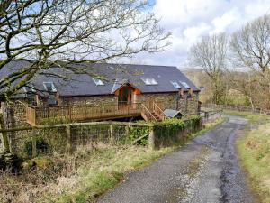 a house with a fence next to a dirt road at Coed Y Nant Barn in Cilybebyll