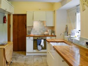 a kitchen with white cabinets and a stove top oven at Bryn Ysgol in Yspytty-Ifan