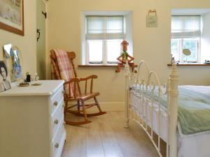 a bedroom with a bed and a chair and windows at Bryn Ysgol in Yspytty-Ifan