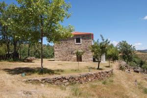 a stone house with a stone wall and trees at Casa da Janal in Vimioso