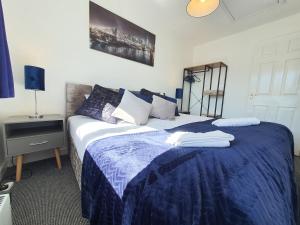 een slaapkamer met een bed met een blauw dekbed bij Thesiger Court Apartments - Free Private Parking - by Property Promise in Cardiff
