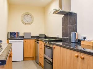 a kitchen with wooden cabinets and a clock on the wall at Hengegin - Uk39874 in Llandybie