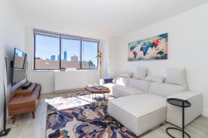 LUXURY DESIGNER GREENWICH VILLAGE 1BR HEAVEN!! BEAUTIFUL PANORAMIC CITY VIEWS! في نيويورك: غرفة معيشة مع أريكة بيضاء وتلفزيون