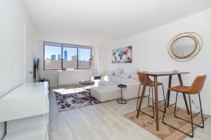 LUXURY DESIGNER GREENWICH VILLAGE 1BR HEAVEN!! BEAUTIFUL PANORAMIC CITY VIEWS! في نيويورك: غرفة معيشة بيضاء مع أريكة بيضاء وطاولة