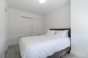 LUXURY DESIGNER GREENWICH VILLAGE 1BR HEAVEN!! BEAUTIFUL PANORAMIC CITY VIEWS! في نيويورك: غرفة نوم بيضاء مع سرير كبير مع شراشف بيضاء