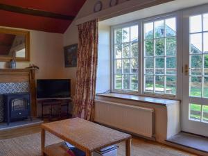 ein Wohnzimmer mit einem Kamin und einem großen Fenster in der Unterkunft Birkerthwaite Cottage-w41479 in Eskdale
