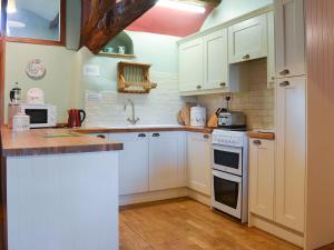 a kitchen with white cabinets and white appliances at Birkerthwaite Cottage-w41479 in Eskdale