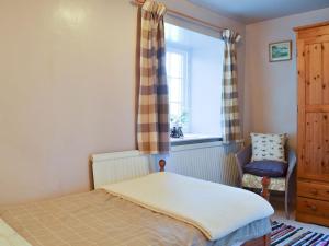 a bedroom with a bed and a chair and a window at Birkerthwaite Cottage-w41479 in Eskdale