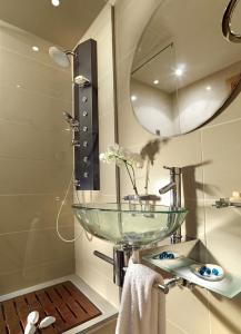 a bathroom with a glass sink and a mirror at Out Of The Blue Resort & Spa in Agia Pelagia