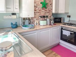 a kitchen with white cabinets and a brick wall at Star Yard in Tenbury