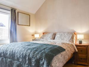 a bedroom with a bed with a blue comforter and a window at Star Yard in Tenbury