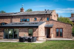 a brick house with glass doors and windows at No1 Little Barrow Barns - Sleeps 10 in Chester