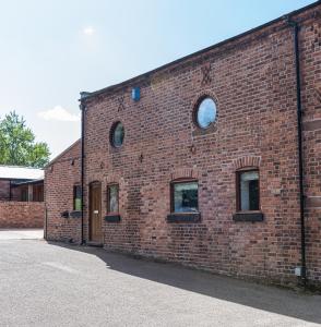 a brick building with three windows on it at No1 Little Barrow Barns - Sleeps 10 in Chester