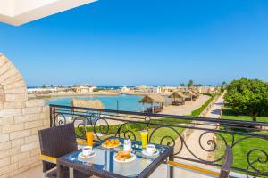 einen Balkon mit einem Tisch und Stühlen mit Blick auf das Wasser in der Unterkunft Aladdin Beach Resort - Families and Couples Only in Hurghada