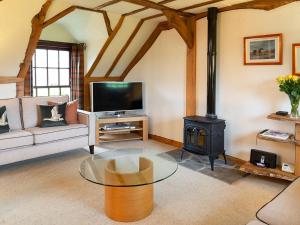 a living room with a glass table and a stove at Fochy Cottage in Milnathort